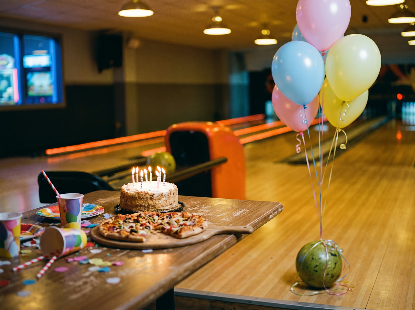 Ein Geburtstagstisch neben der Bahn: Torte mit Kerzen, Pizza, bunte Becher und Ballons