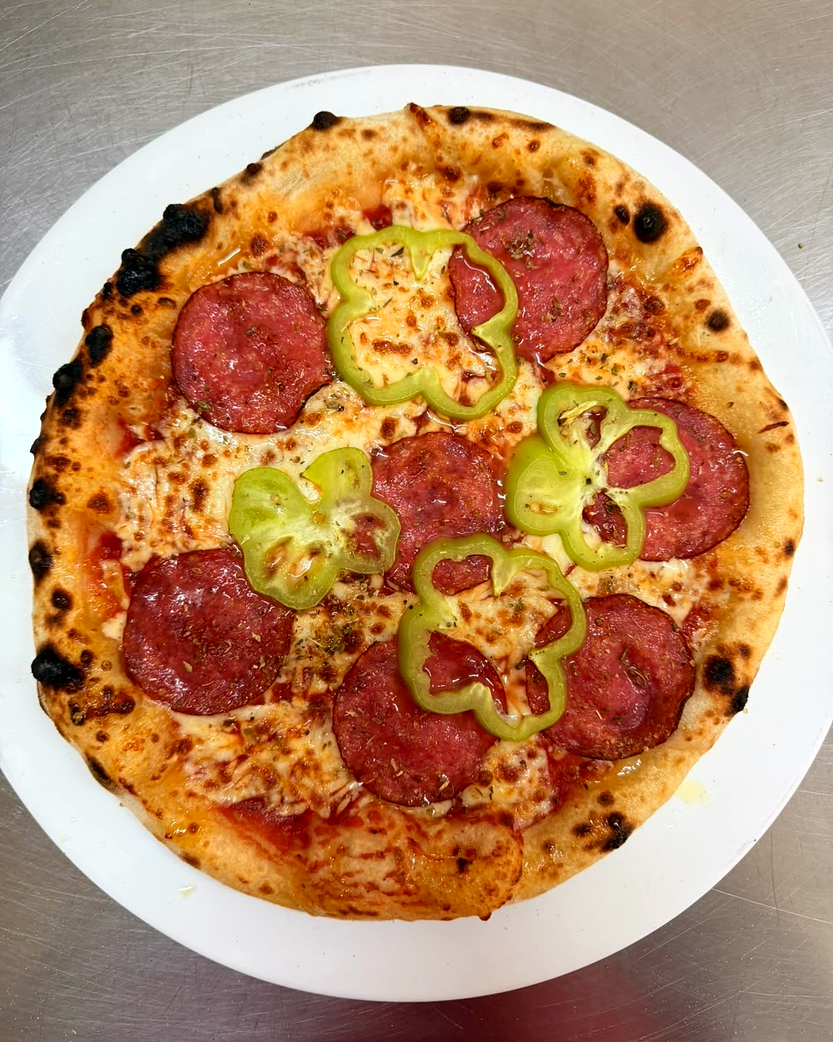Eine Pizza mit Salami und Paprika, frisch aus dem Ofen